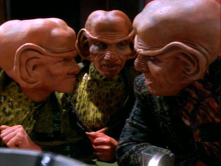 Three Ferengi males with their heads together in a secretive conspiratorial huddle in Star Trek: Deep Space Nine