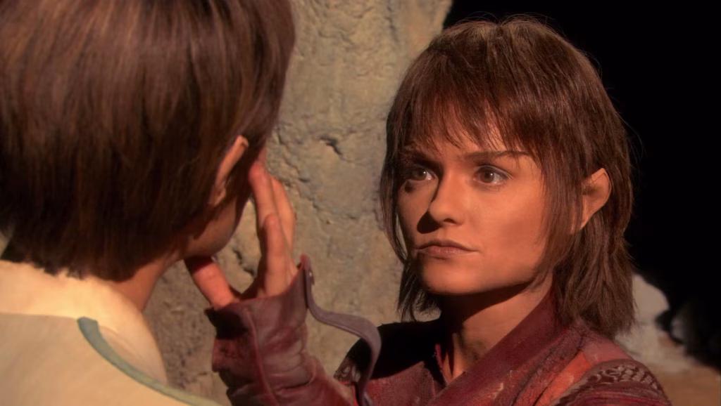 A young Vulcan woman touches another person’s face during a telepathic or ceremonial moment.