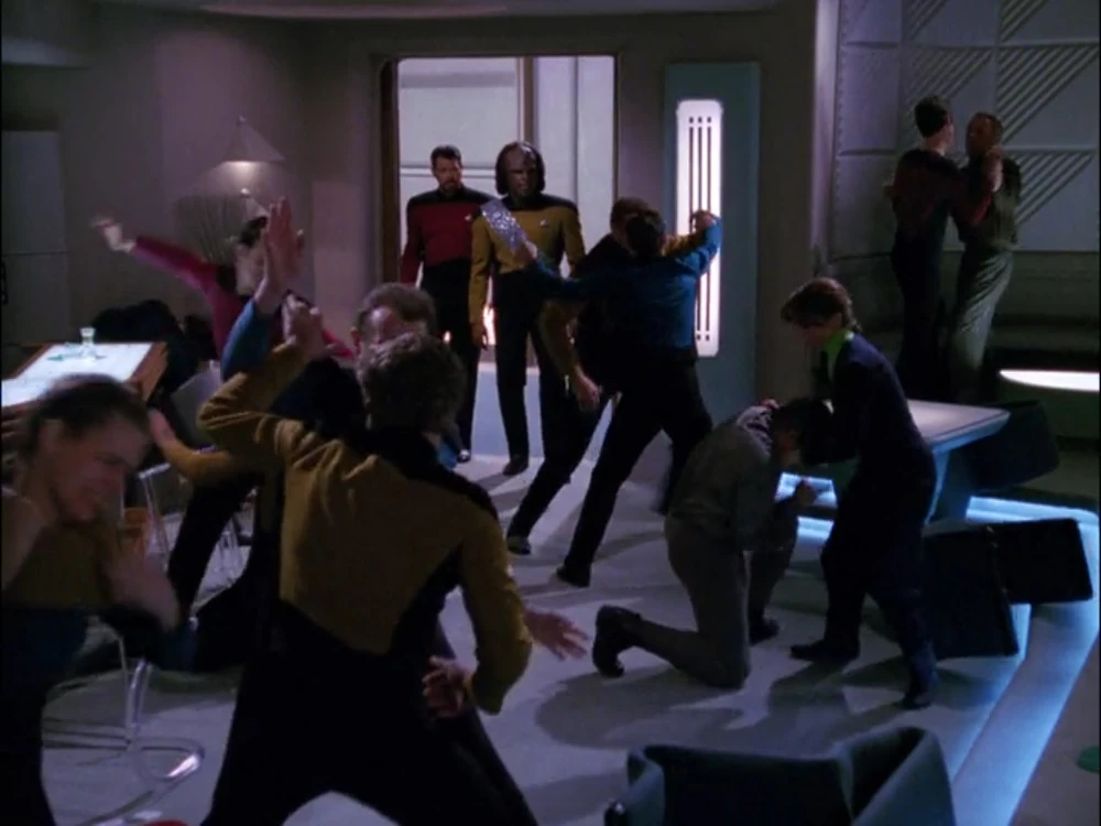 Starfleet crew members fight one another during a brawl inside a starship lounge.