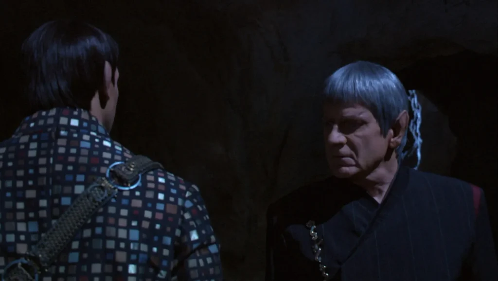 Two Vulcan men confront each other in a darkened room.